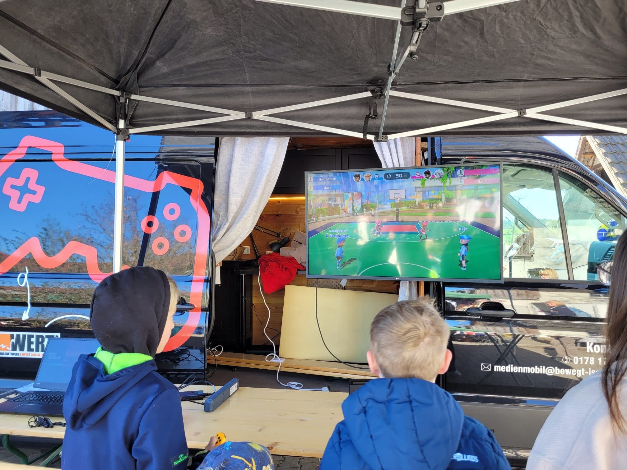 Gaming Café — Kinder spielen gemeinsam am großen Bildschirm